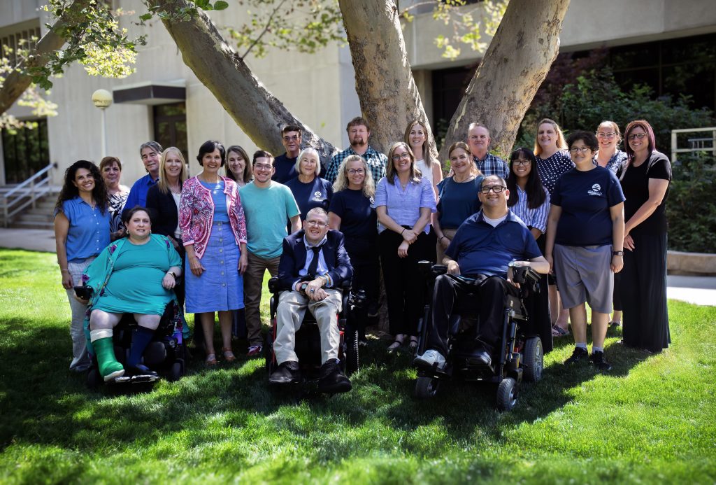 group photo of council members outside on the lawn with a tree and building in the background